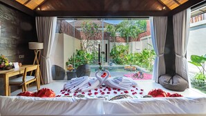 Una stanza con un letto, una scrivania, una lampada e vista su un giardino e una piscina esterni.