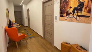 Un pasillo con piso de madera, una puerta, un cartel y una silla.
