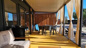 Zona d'estar a l'aire lliure coberta, amb taula i cadires, un sofà i un terraço de fusta.