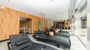 Un espace spa moderne avec des fauteuils noirs, des panneaux muraux en bois et une entrée en verre.