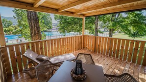 A wooden deck with a table and chairs, overlooking a swimming pool and greenery. - Thermal Canopy Tree House With Riviera Tickets (Brežice)