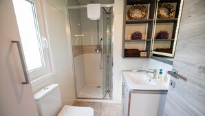 A modern bathroom with a glass-enclosed shower, a toilet, and a sink with a mirror above it. - Thermal Canopy Tree House With Riviera Tickets (Brežice)