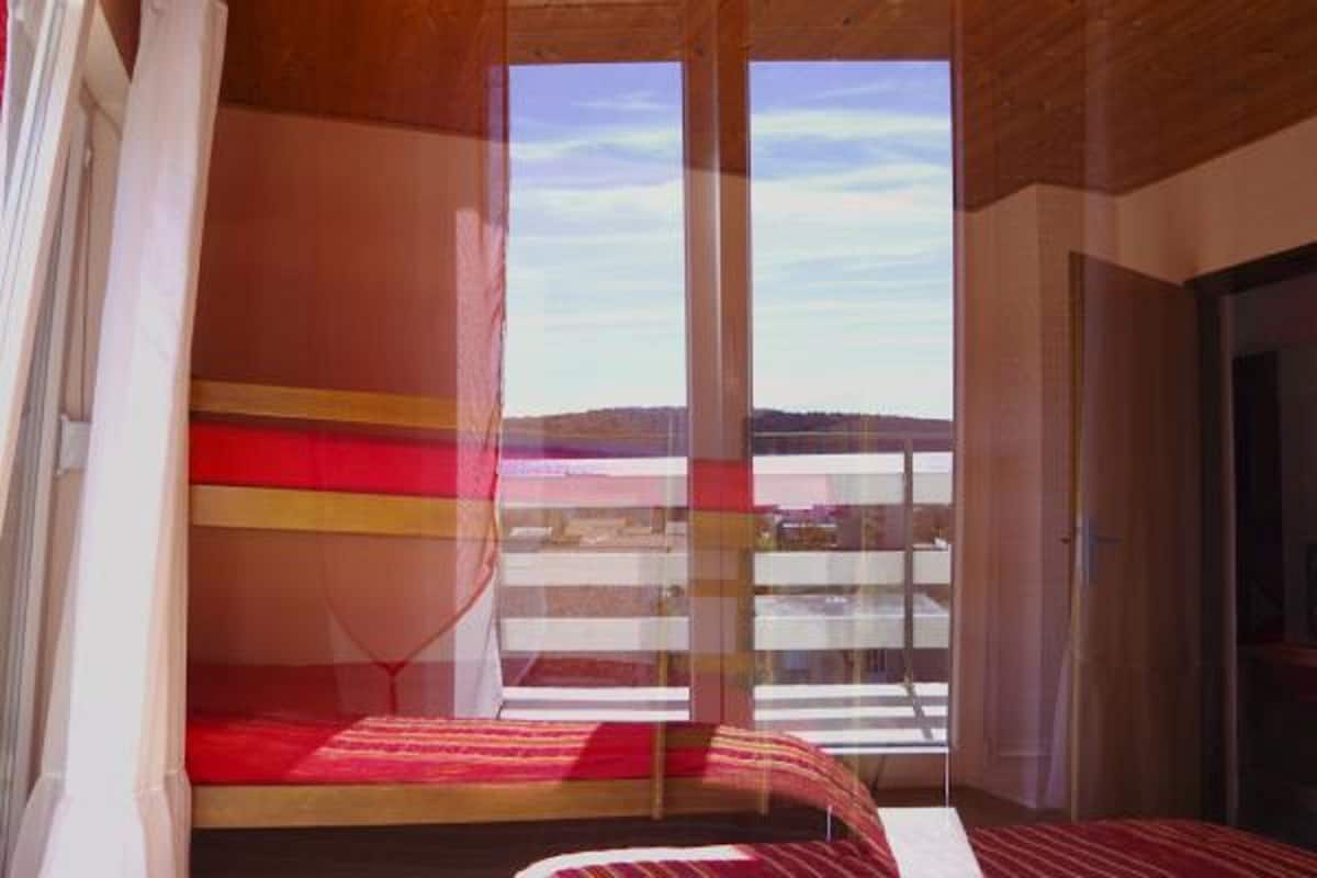 A bedroom with a bed, a window, and a view of the outdoors.