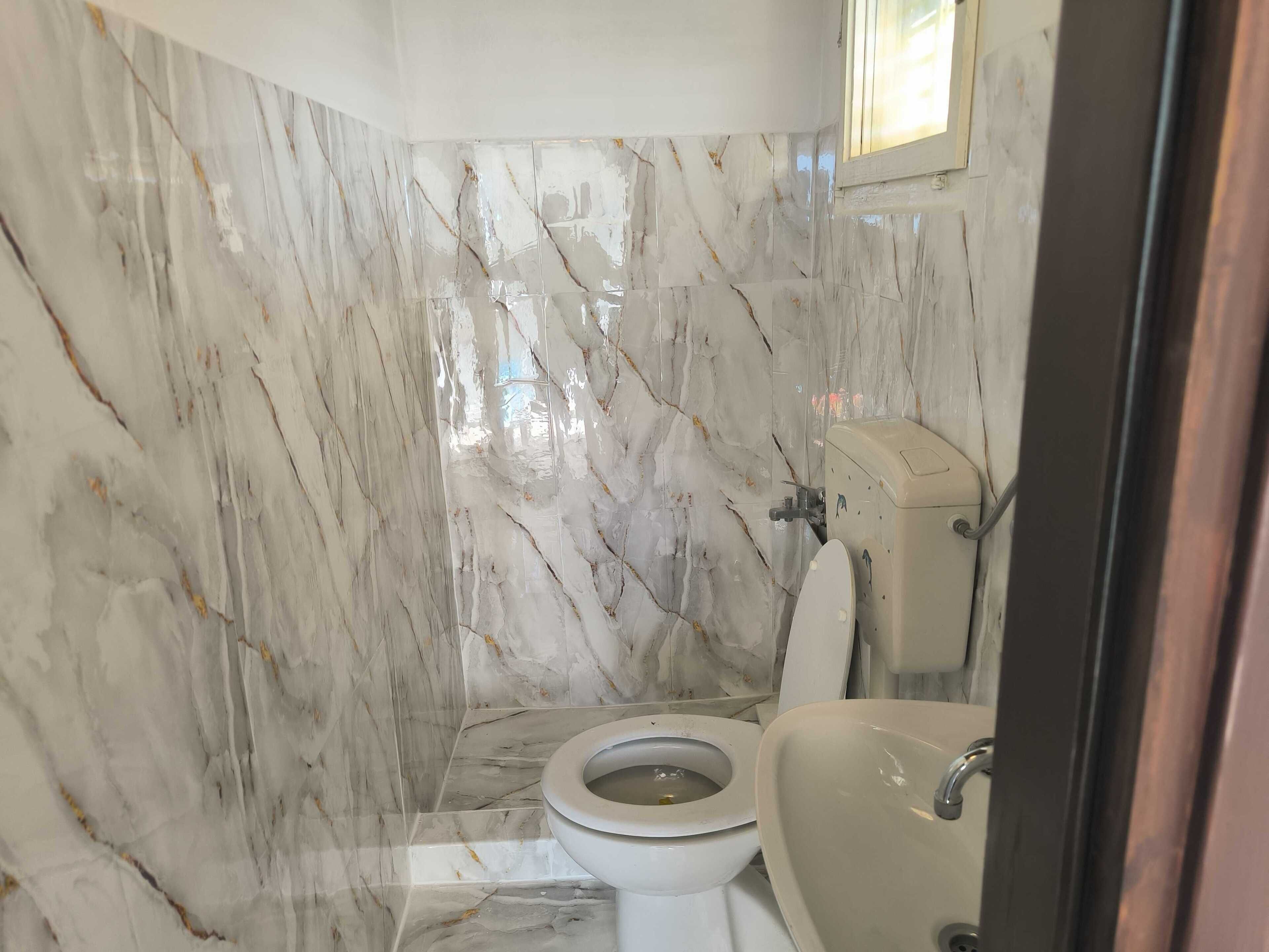 Une salle de bain avec des murs en marbre, des toilettes et un lavabo.