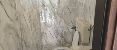 Une salle de bain avec des murs en marbre, des toilettes et un lavabo.