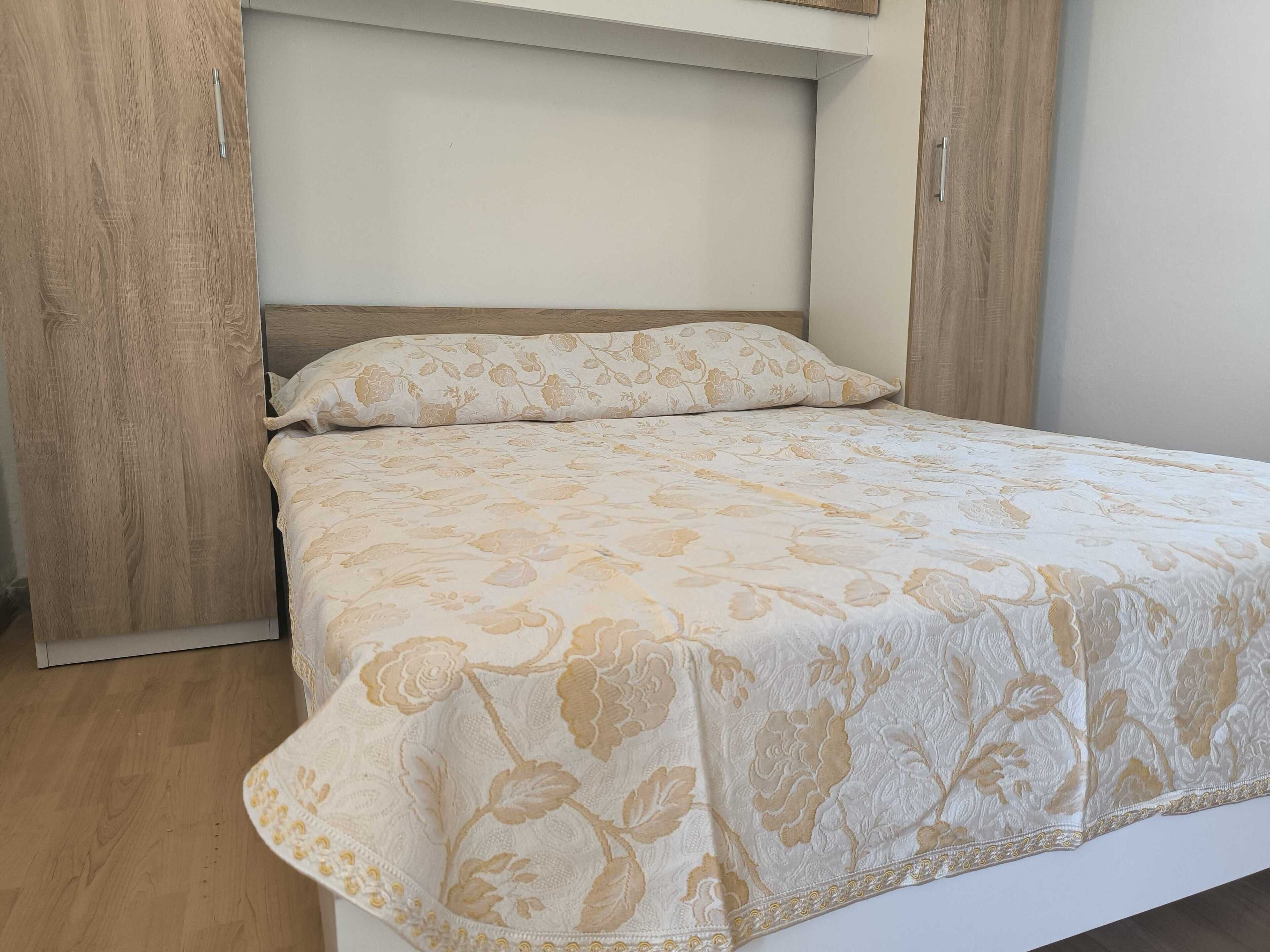 A bedroom with a bed, a headboard, and wooden wardrobes.