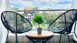 A balcony with two black wire chairs, a small wooden table, and a potted plant. - Staroot Residences  (Nairobi)