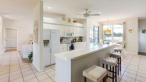 A modern kitchen with white cabinetry, a central island, and bar stools.