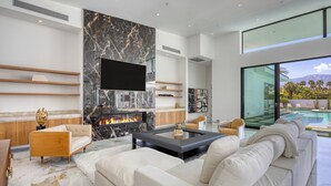 Un salon moderne avec une cheminée, un grand téléviseur et une vue sur la piscine.