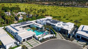 Un hôtel moderne doté d’une piscine sur le toit, entouré d’une végétation luxuriante et avec une vue sur les montagnes en arrière-plan.