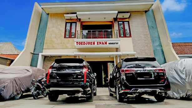 A building with a sign reading "TOEDJOEH ENAM HOMESTAY" and two parked SUVs in front. - Hotel O 76 Gayungsari (Surabaya)