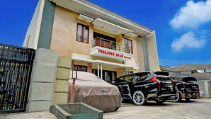 A two-story building with a covered carport and a black car parked in front. - Hotel O 76 Gayungsari (Surabaya)
