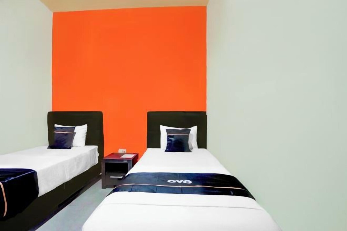 A hotel room with two beds, each with a black headboard, white bedding, and a blue accent.