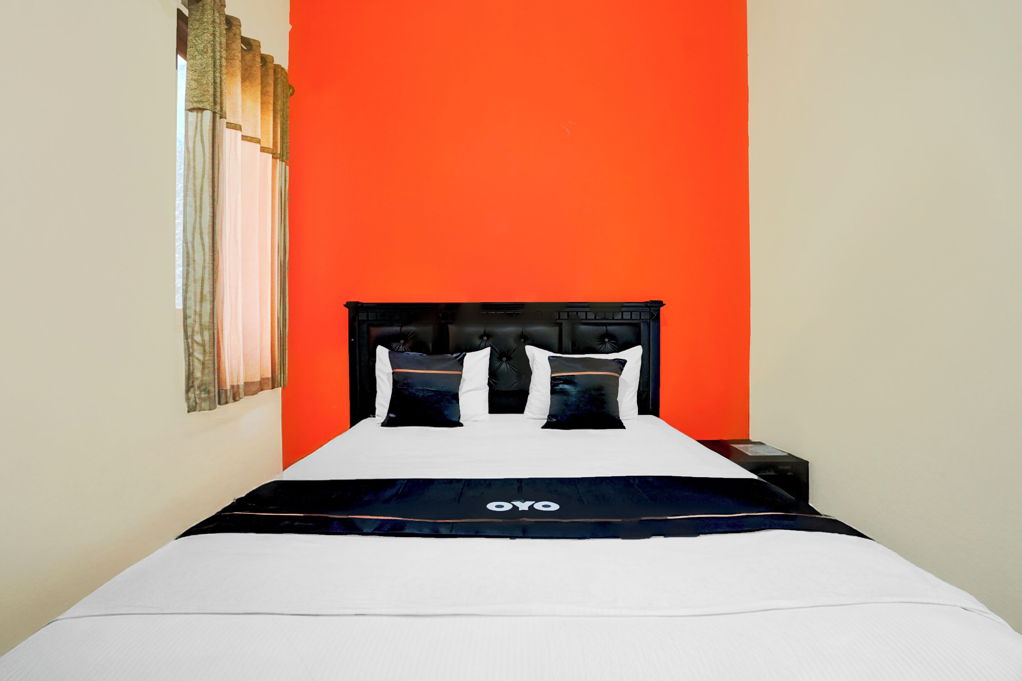 Ein Bett mit schwarzem Kopfteil, weißer Bettwäsche und einem schwarz-weißen Kopfkissen.