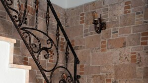 A staircase with ornate black metal railings and a brick wall background. - KAYA KORUĞU CUNDA (Ayvalik)