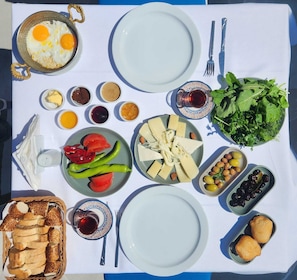 A table set with various dishes including eggs, cheese, olives, and vegetables, suggesting a meal setup. - KAYA KORUĞU CUNDA (Ayvalik)