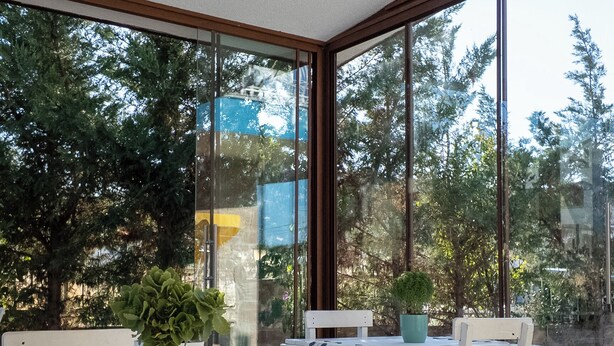 A sunroom with large windows, white furniture, and a ceiling light fixture. - KAYA KORUĞU CUNDA (Ayvalik)