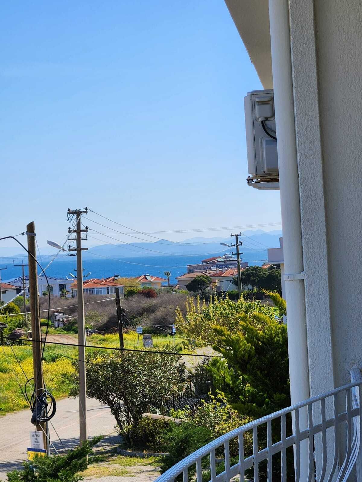 A balcony overlooking a coastal area with houses, power lines, and a clear sky.