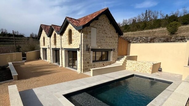 Un bâtiment en pierre avec une piscine devant.