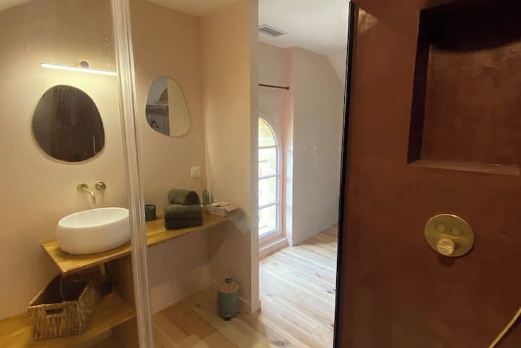 Un baño moderno con un espejo redondo, un lavabo blanco y un mueble de tocador de madera.