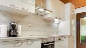 Una cocina moderna con armarios blancos, horno integrado y cafetera.