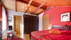 Un dormitorio con techo de madera, colcha roja y cabecera de madera.