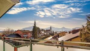 Vista desde un balcón sobre un pueblo con casas tradicionales, una iglesia y montañas al fondo.