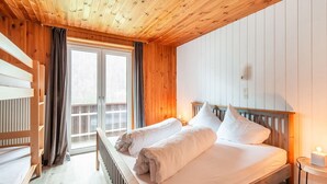 A wooden cabin bedroom with a bed, a window, and a radiator.