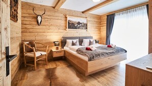 Een houten kamer met een bed, een stoel, een nachtkastje, een aan de muur bevestigd schedel, en een lijst met een afbeelding.