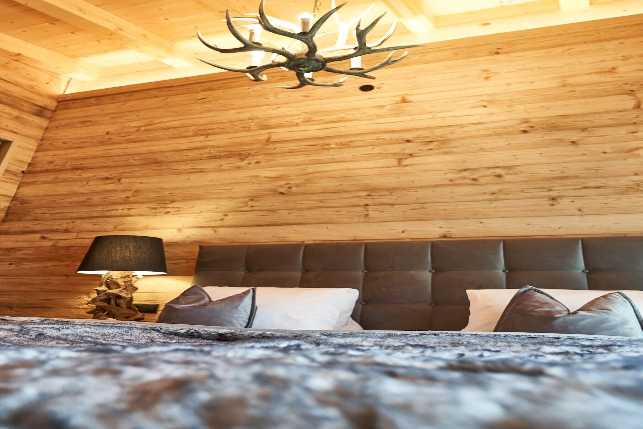 Een houten interieur met een bed, een lamp en een kroonluchter.