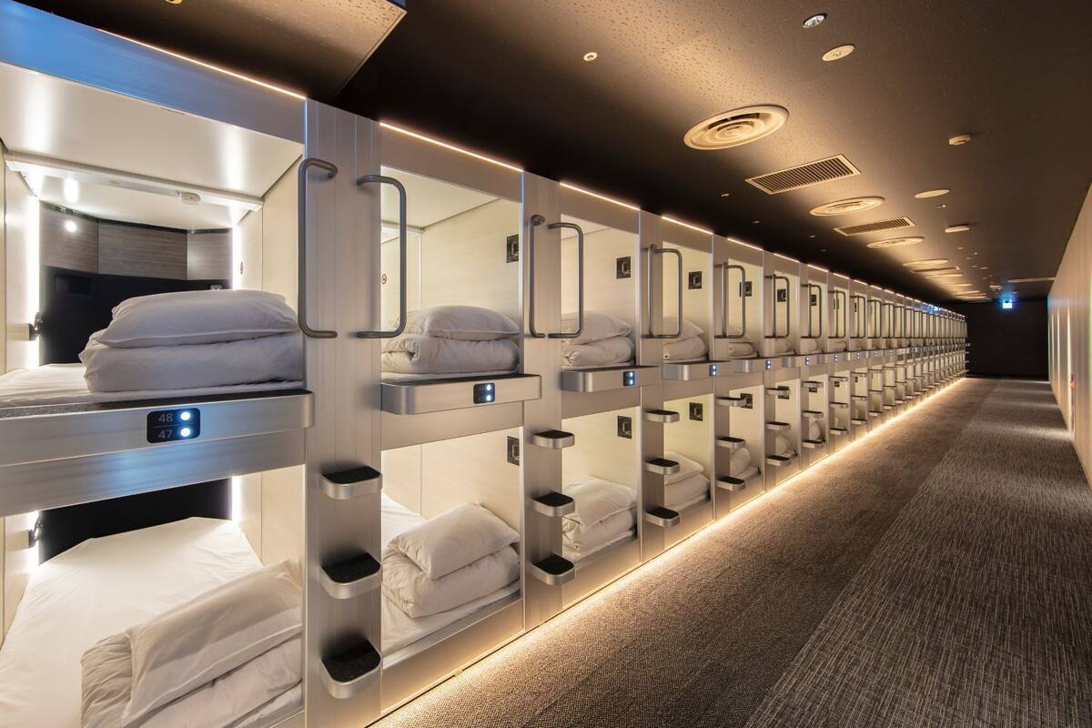 A row of bunk beds with individual headboards and bedside tables, each with a control panel.