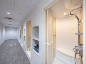A modern bathroom with a shower, toilet, and storage shelves. - STATION INN THE URASHIMA (Onomichi)