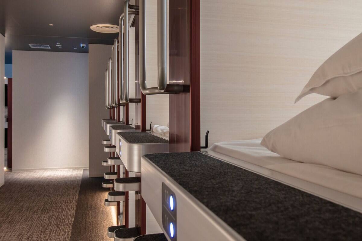A hotel bathroom with multiple sinks and a single bed.