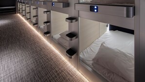 A row of bunk beds with built-in desks and mirrors, each with a control panel. - STATION INN THE URASHIMA (Onomichi)