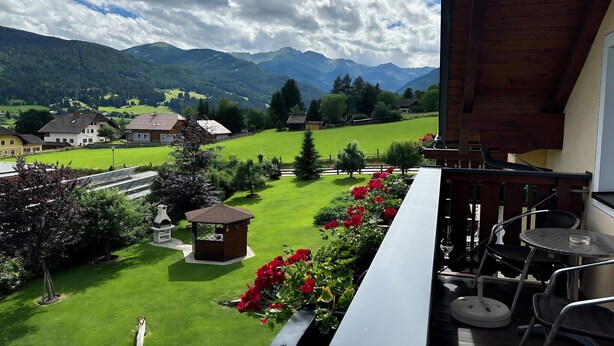 A balcony with a view of a green landscape, a wooden structure, and a small table with chairs. - Apartment in Lungau near Ski Lift (St Michael im Lungau)