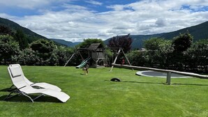 A grassy outdoor area with a swing set, a seesaw, and a lounge chair. - Apartment in Lungau near Ski Lift (St Michael im Lungau)