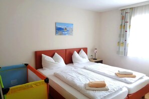 Habitación de hotel con cama, almohadas, mesita de noche, lámpara y un cuadro en la pared.