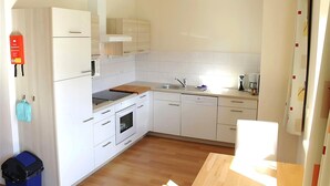 A modern kitchen with white cabinets, a built-in oven, a sink, and a countertop with a kettle and other small appliances. - Apartment in Lungau near Ski Lift (St Michael im Lungau)