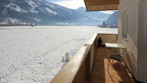 A balcony with a view of a snow-covered landscape and mountains.
