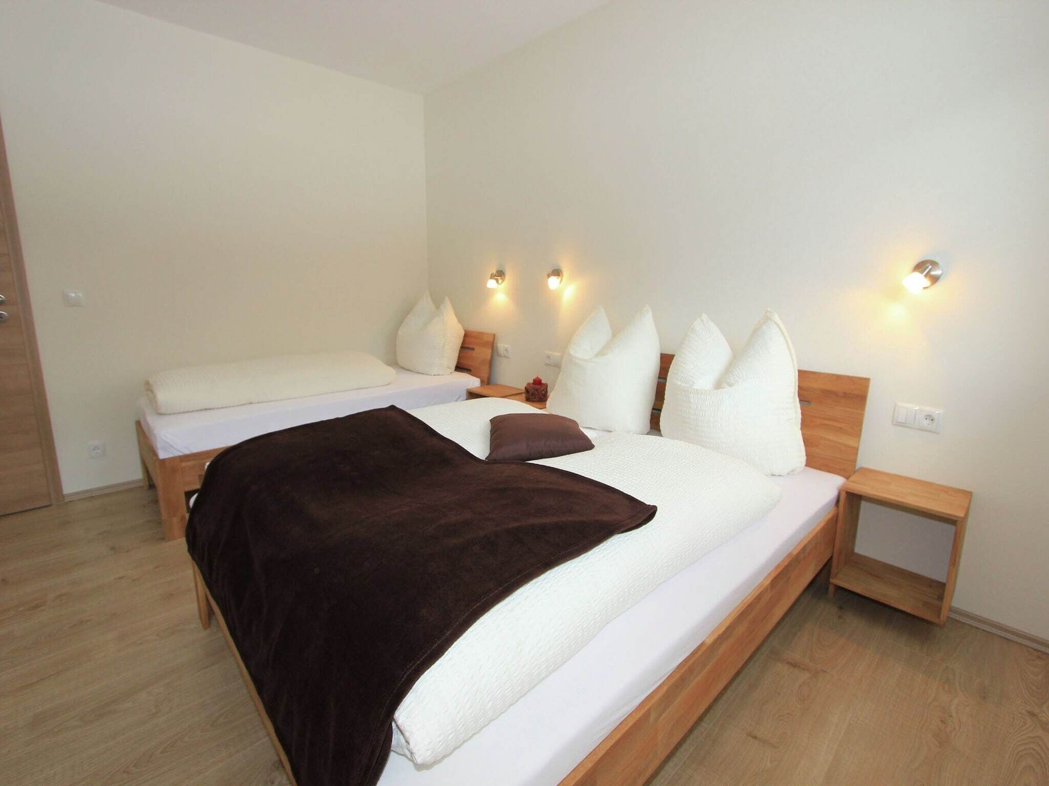 Een moderne slaapkamer met twee bedden, houten hoofdborden en nachtlampjes.