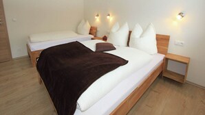 A modern bedroom with two beds, wooden headboards, and bedside lamps.