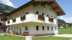 A two-story building with balconies, a covered patio area, and a view of a mountainous landscape.