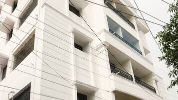 A multi-story building with balconies, a gated entrance, and a parked motorcycle.