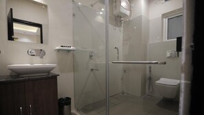 A modern bathroom with a glass-enclosed shower, a white sink, and a toilet. - Hotel Vista Suites (Tezpur)