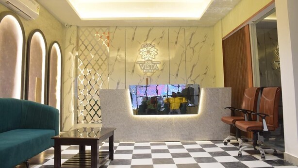 A hotel lobby with a checkered floor, a sofa, a reception desk, and a seating area with chairs. - Hotel Vista Suites (Tezpur)