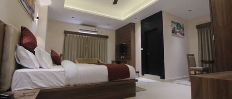 Un dormitorio moderno con una cama grande, ventilador de techo, aire acondicionado y televisor.