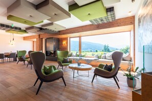 A modern interior with wooden flooring, green and grey chairs, a round table, and a large window offering a mountain view. - Chalet in Wölting in a delightful area. (Wölting)