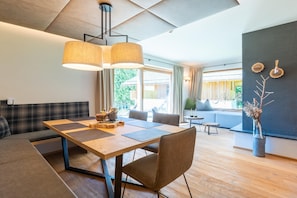 Uma sala de estar moderna com uma mesa de jantar de madeira, um sofá e uma janela grande com vista para o verde.