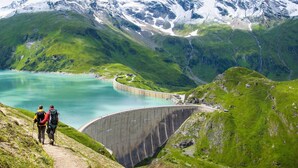 Un barrage avec une route menant à une région montagneuse où se trouve un lac.