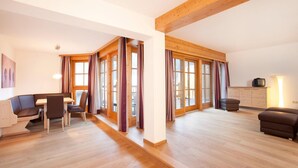 A spacious living area with a wooden floor, a sofa, a dining table with chairs, and a television. - Chalet in Pinzgau near Ski Slopes (Wald im Pinzgau)